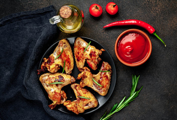 Grilled chicken wings on a plate with spices on a stone background 