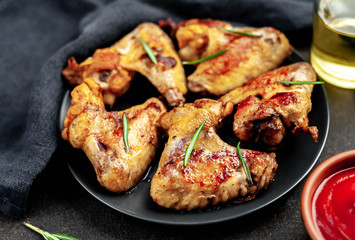 Grilled chicken wings on a plate with spices on a stone background 