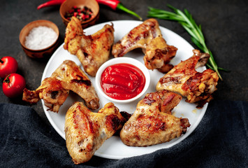 Grilled chicken wings on a plate with spices on a stone background 