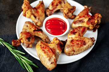 Grilled chicken wings on a plate with spices on a stone background 