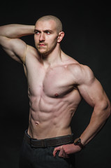 Fototapeta na wymiar Sporty sexy man stands Topless on a dark background. Sports, beauty