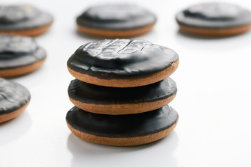 Round cookies covered in chocolate lie on top of each other on a white vertical background with copy space at the bottom. The concept of making homemade pastry and dessert