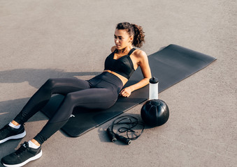Fototapeta na wymiar Female in sportswear lying on an exercise mat with a medicine ball, skipping rope and bottle