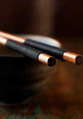 Naklejka premium Wooden Chopsticks and ceramic Bowl on rustic background. Close up. 