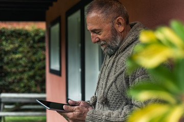 man interacting with his cell phone in the front yard of his house