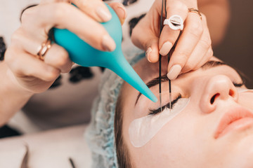 The procedure for eyelash extensions using the beam method - blowing and drying glued eyelashes on the eyelid of the client