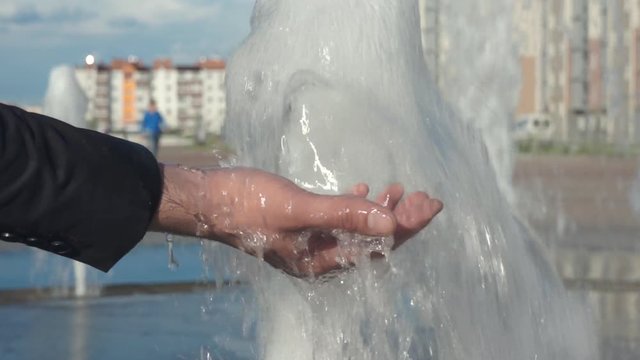 A man wets his hand in the fountain. Hand close-up.