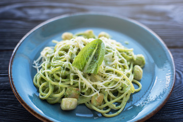 Green Pasta with scallop and sauce on blue plate