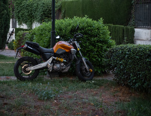 Moto naranja y negra aparcada con paisaje verde