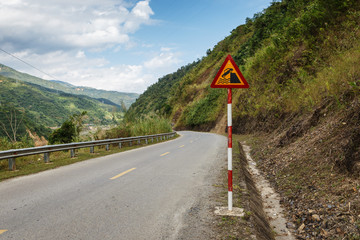 Quayside or river bank. Road sign on a mountain road in Vietnam.