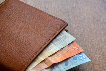 New leather wallet with euro money on a wooden background