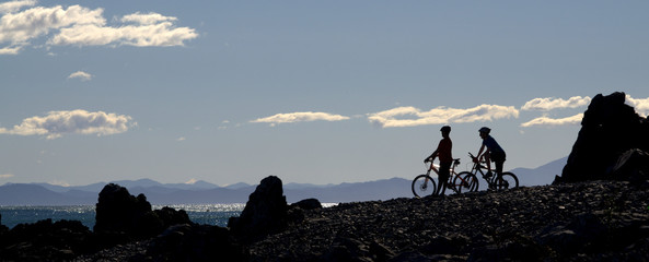 Cyclists silhouette against blue sky, New Zealand.