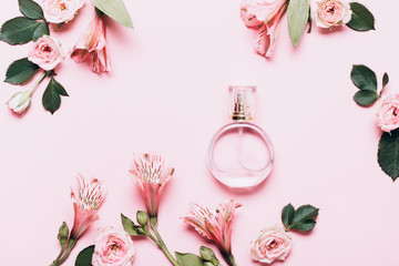 Women's perfume bottle and roses flowers on pink background. Creative Layout, copy space