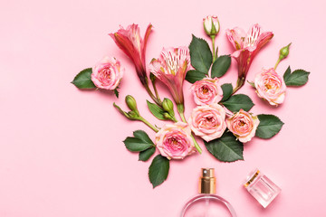 Bottle of perfume and flower arrangement of rosebuds on pink background