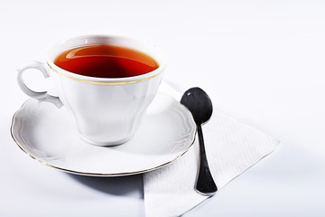Obraz na płótnie Canvas cup of tea on white background. White porcelain cup with black tea with teaspoon and napkin on white background. Tea for breakfast. Five o'clock tea. 