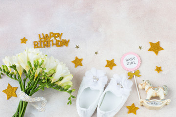Fototapeta na wymiar bouquet of white freesia, booties, toy, inscription happy birthday and stars