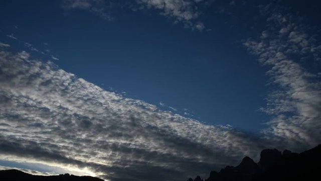 un tramonto ricco di piccole nuvole in movimento, bellissime nuvole a cumuli in montagna si muovono portate dal vento in un cielo di colore blu 