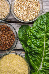 Flat lay shot of glass bowls full of cereals and a chard leaf