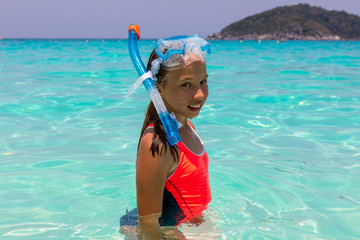 Happy child girl in a mask on the beach in summer