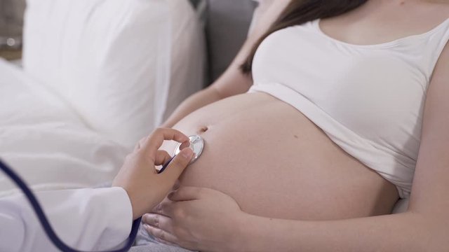 expectant asian woman being examined by obstetrician with equipment to make sure her baby is in good condition. routine prenatal checkup concept