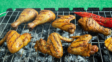 chicken wings legs on grill grate cooking process green grass  background outdoors