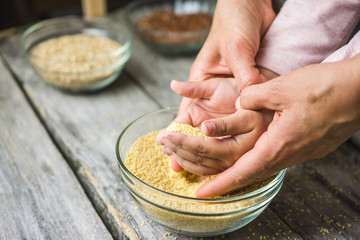 Mother and child's hands grabbing millet seeds from the glass bowl