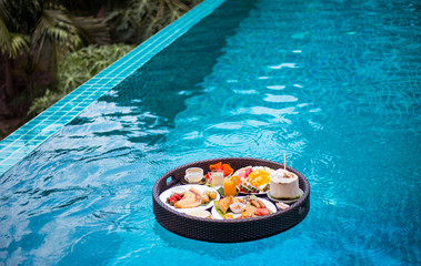 Breakfast in swimming pool, floating breakfast in tropical resort. Fruit plate by resort pool.