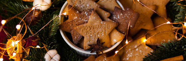 Homemade cookies with the french text Happy Holidays! Handmade freshly backed gingerbread biscuits served in a white bowl and decorated with the fir, citrus, cotton, anise and cinnamon. Banner