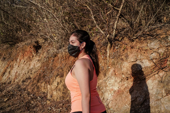 La joven est&aacute; haciendo ejercicios protegida con su cubreboca en la monta&ntilde;a.