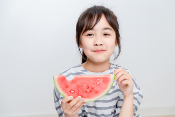 Asian little girl eating watermelon at home