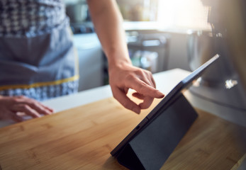 Woman Using Touch Screen on a Digital Tablet In The Kitchen At Home
