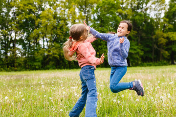 Two adorable girls dancing on the meadow