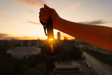 Hand with medal on sunrise