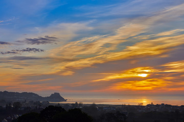 Image of Grouville bay with Gorey castle in the background with a smooth sea at sunset. Jersey Channel Islands