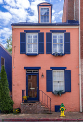 Fototapeta na wymiar Street view of an old colonial house in historic Annapolis Maryland with peach, pink walls and contrasting dark blue shutters, dormer window