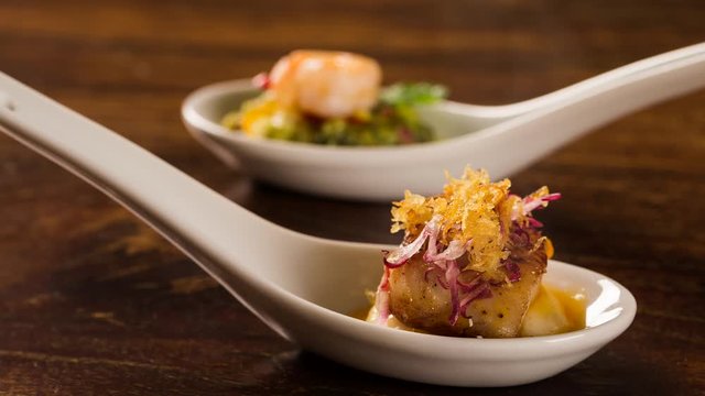 Slide shot Grilled fish with reduction of yellow fruits and aligot baiano in a spoon. Taste gastronomy finger food with smoke.