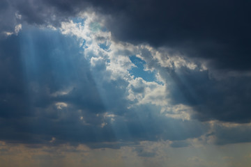 Obraz premium Heavenly Sun Rays Through Dark Clouds Against The Blue Sky. selective focus