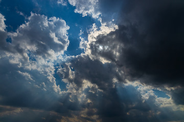 Obraz premium Heavenly Sun Rays Through Dark Clouds Against The Blue Sky. selective focus