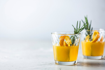 Two glasses of honey bourbon cocktail with rosemary simple syrup or homemade whiskey sour cocktail drink with orange and rosemary decoration orange peel, jar of honey and bartender tools