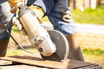 A man processes rusty metal structures with a manual grinder.