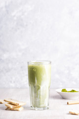 Glasses of matcha latte with coconut milk and white chocolate on wooden and marble background