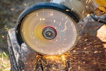 A man processes rusty metal structures with a manual grinder.