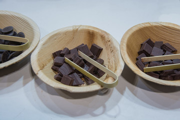 Chocolate in three beige bowls and tweezers