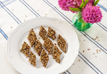 Keto diet. Delicious, healthy multi-slag  peanut brittle from flax, sesame, and sunflower seeds are placed on a white plate. Close up.