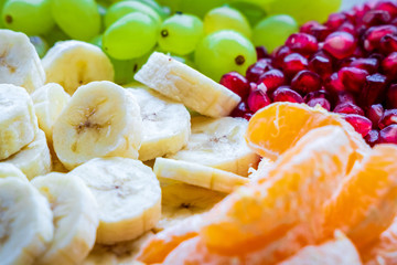 Healthy Breakfast Concept. Fresh fruits on the breakfast table. Close up of Grapes, banana, oranges, pomegranate. selective focus