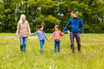 young familiy are walking through a green field