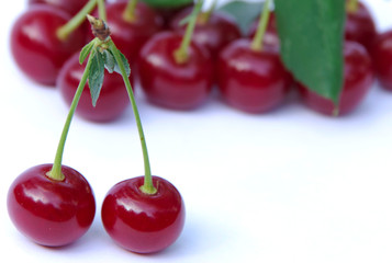 Two ripe juicy cherries on a white surface.