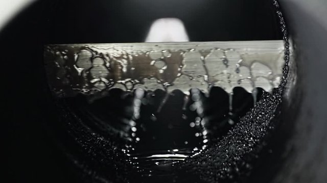 Close up shot of Sharp Steel Saw Cutting Metal Tube Water is Pouring Down Automated Line of Modern Factory