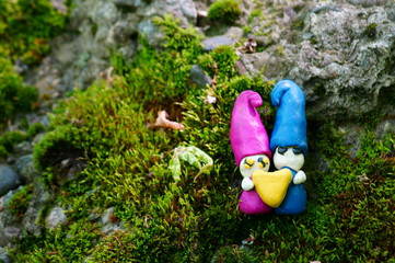 Two gnome out of clay holding a heart. Fabulous figures on a beautiful colored background.