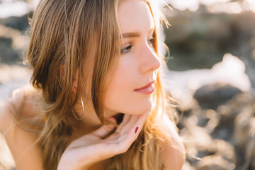 girl in swimwear enjoying and walking on beach, in summer time, on the sunset. Portrait of happy young woman smiling at sea.